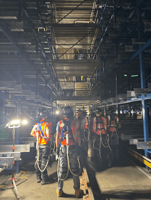 Crew in hi-vis vests and harnesses staging a warehouse racking job